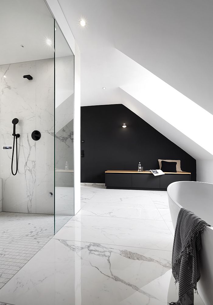 Helles Badezimmer mit Marmorfliesen, einer Glasdusche, einem dunklen Sideboard und einer freistehenden Badewanne in einer Dachschräge.