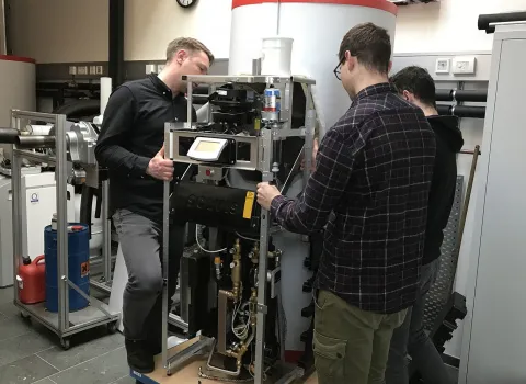 Drei Männer positionieren ein Solvis-Technik-Modul.