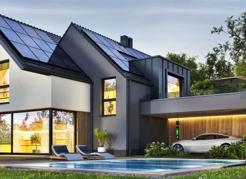 Das Bild zeigt ein energieeffizientes Einfamilienhaus mit Solaranlage, Elektroauto-Ladestation und einem Pool im gepflegten Garten.