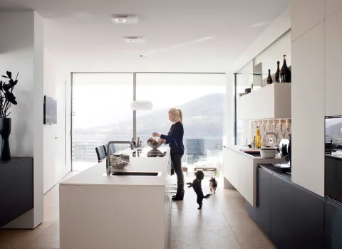 Eine moderne, helle Küche mit großen Fenstern, die Blick auf eine Berglandschaft bieten-.