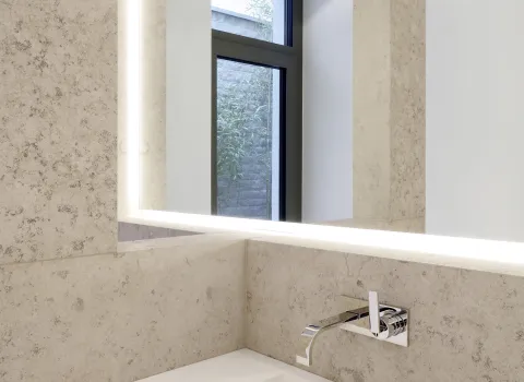 Ein minimalistisches Waschbecken-Design mit integriertem, rechteckigem Becken und einem schlichten, wandmontierten Wasserhahn in Chromoptik.