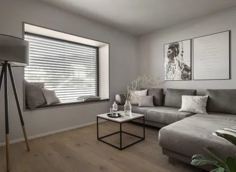 Wohnzimmer mit grauem Sofa, Couchtisch und großer Fensterbank mit Jalousie.