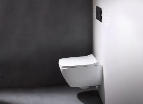 Ein modernes WC der Serie Geberit Smyle ist wandhängend an einer weiß gestrichenen Wand mit kontrastierender dunkler Rückwand installiert.