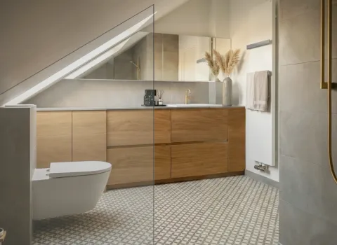 Stilvolles Dachgeschoss-Badezimmer mit minimalistischer Einrichtung, goldenen Akzenten und eleganter Glasdusche.