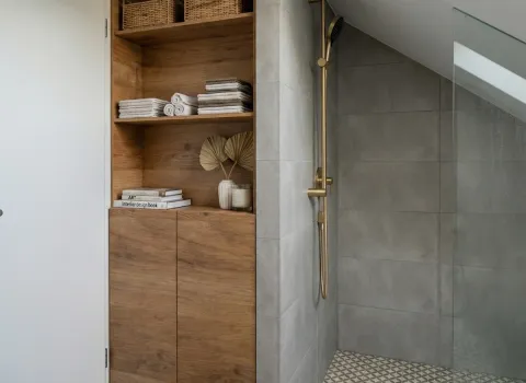 Badezimmer mit platzsparender Dusche im Dachgeschoss, offener Holzablage und modernen Designelementen.
