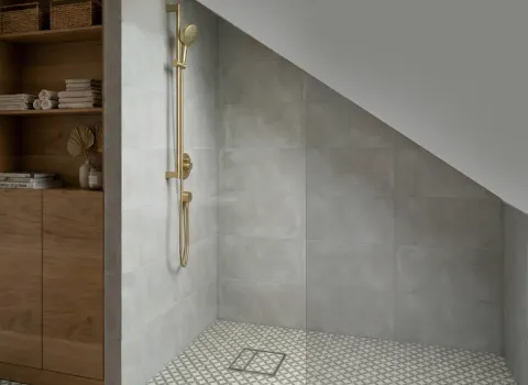 Begehbare Dusche unter der Dachschräge mit goldener Duscharmatur und grauen Wandfliesen im modernen Bad.