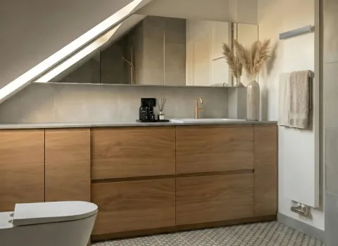 Stilvolles Dachgeschoss-Badezimmer mit minimalistischer Einrichtung, goldenen Akzenten und eleganter Glasdusche.