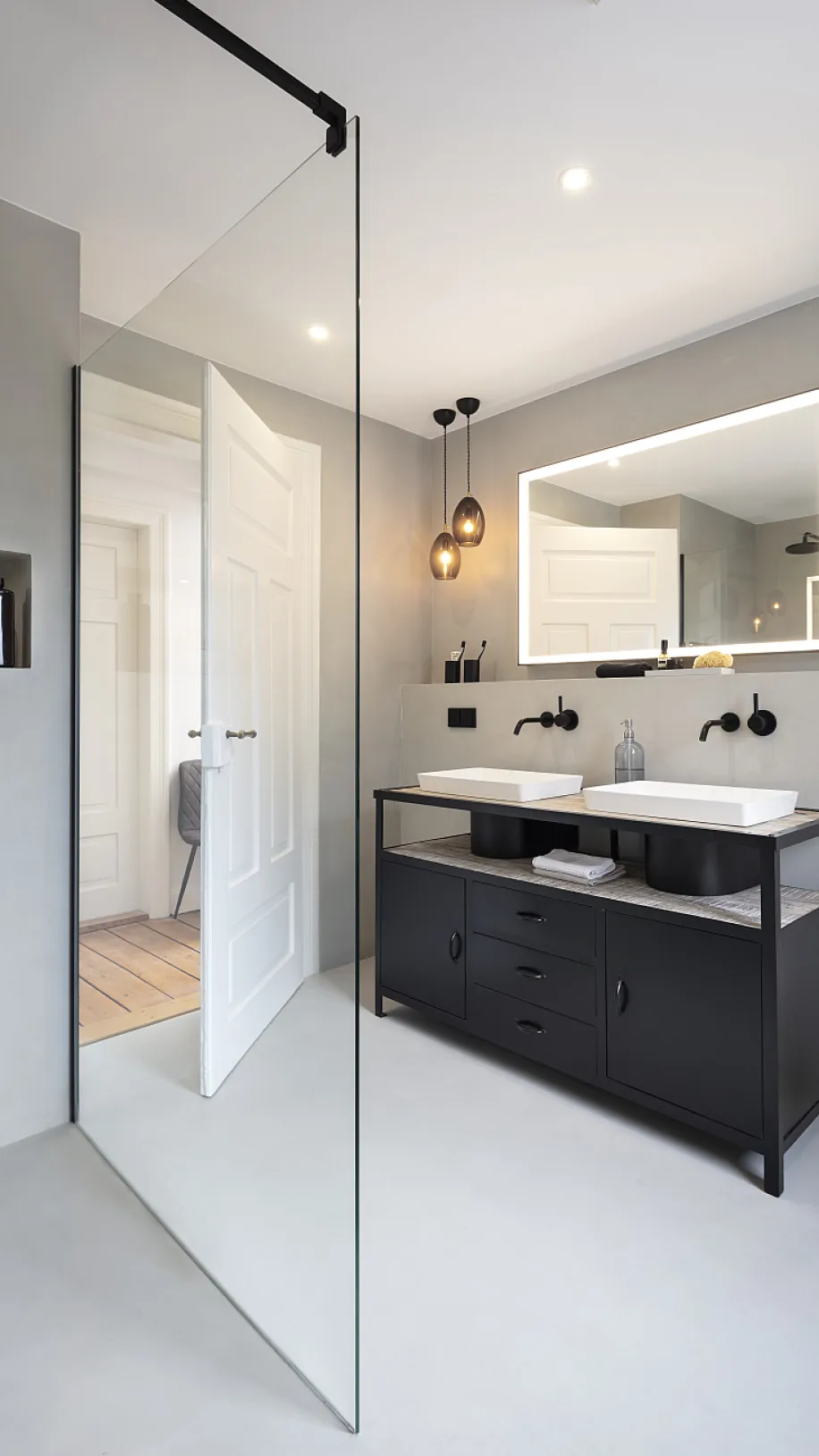 Helles Badezimmer mit Glasdusche und dunklen Waschtisch im industrial style.