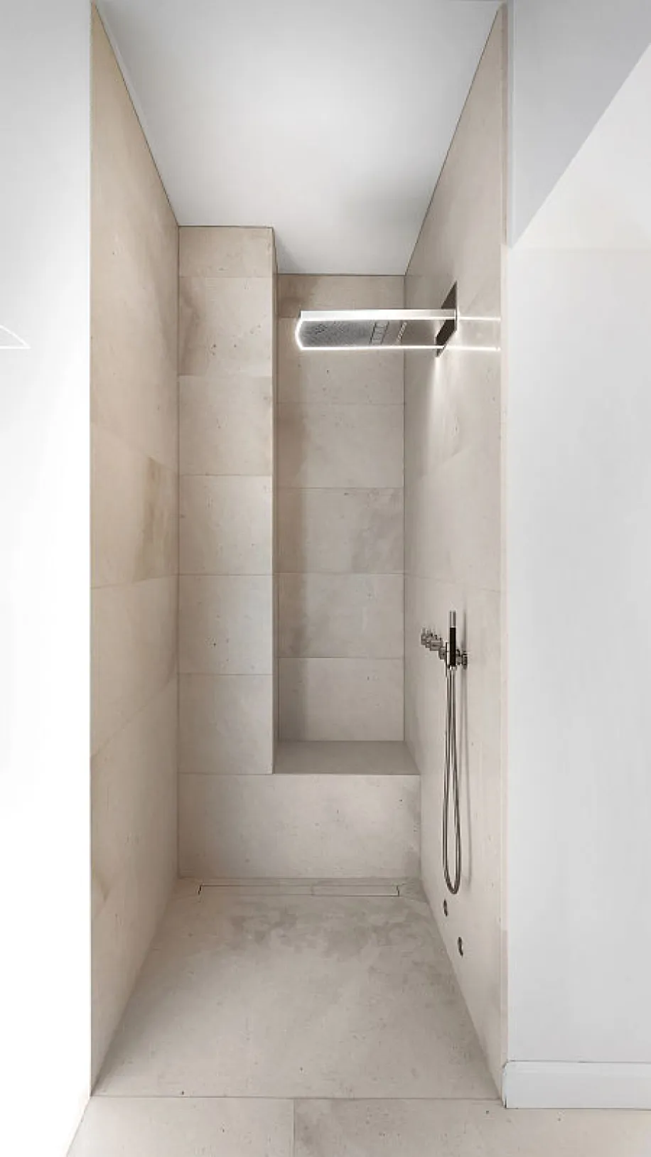 Helle Walk-in-Dusche in modernem Design, gefliest in beigem Naturstein.