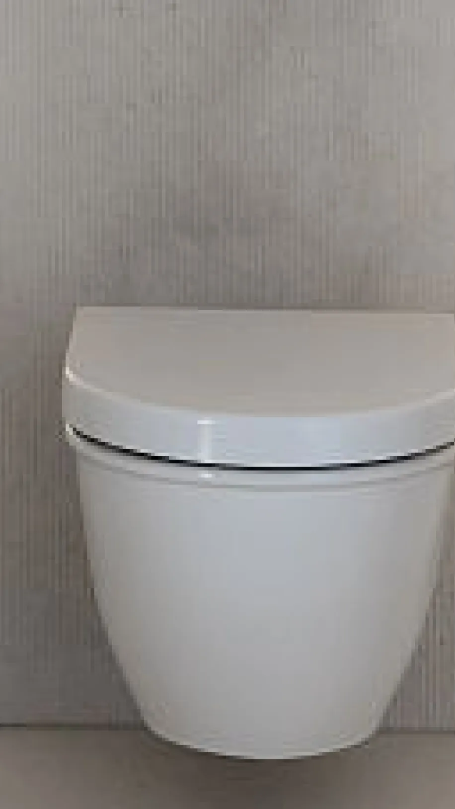 Die Toilette ist wandhängend und in einer Nische mit beigen Wänden und hellen Bodenfliesen installiert. Eine minimalistische Spülplatte ist in die Rückwand eingelassen.
