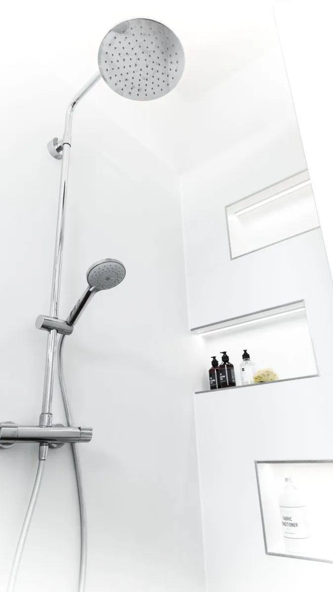 Moderne Dusche mit großer Regendusche und zusätzlicher Handbrause. Zwei eingelassene Nischen in der Wand bieten Platz für Shampoo und Pflegeflaschen.