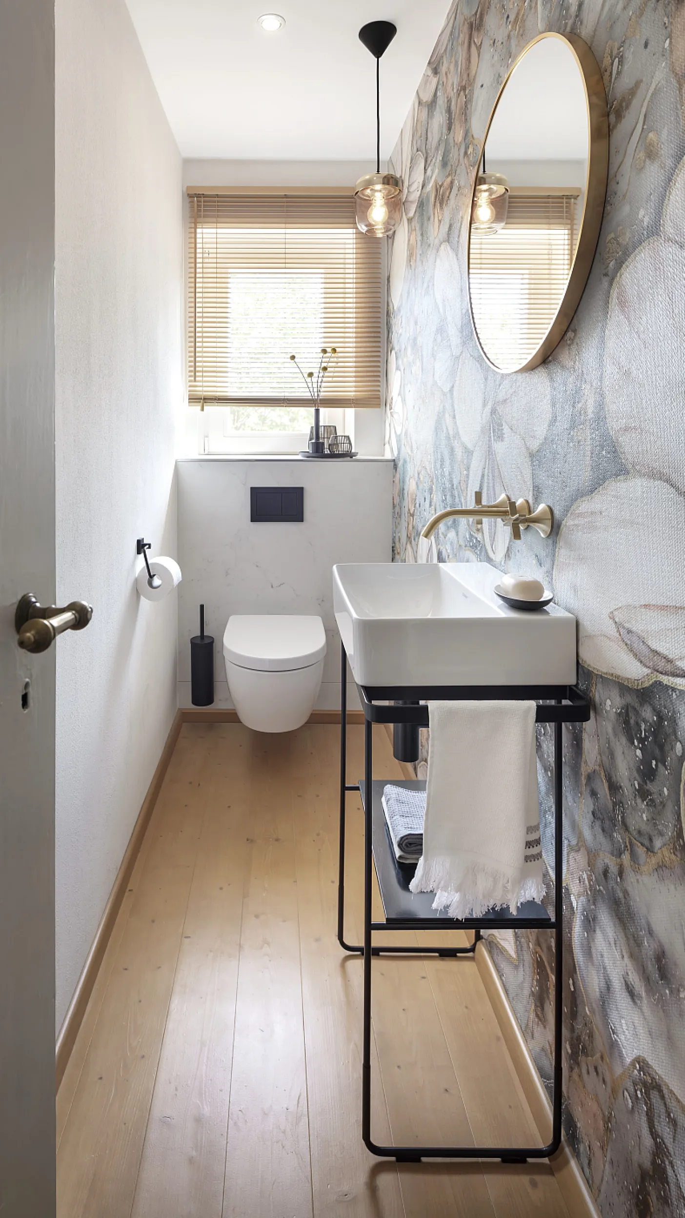 Schmales, schlauchförmiges Gästebad mit Fenster an Stirnseite. Unterhalb des Fensters ist ein wandhängendes WC angebracht.