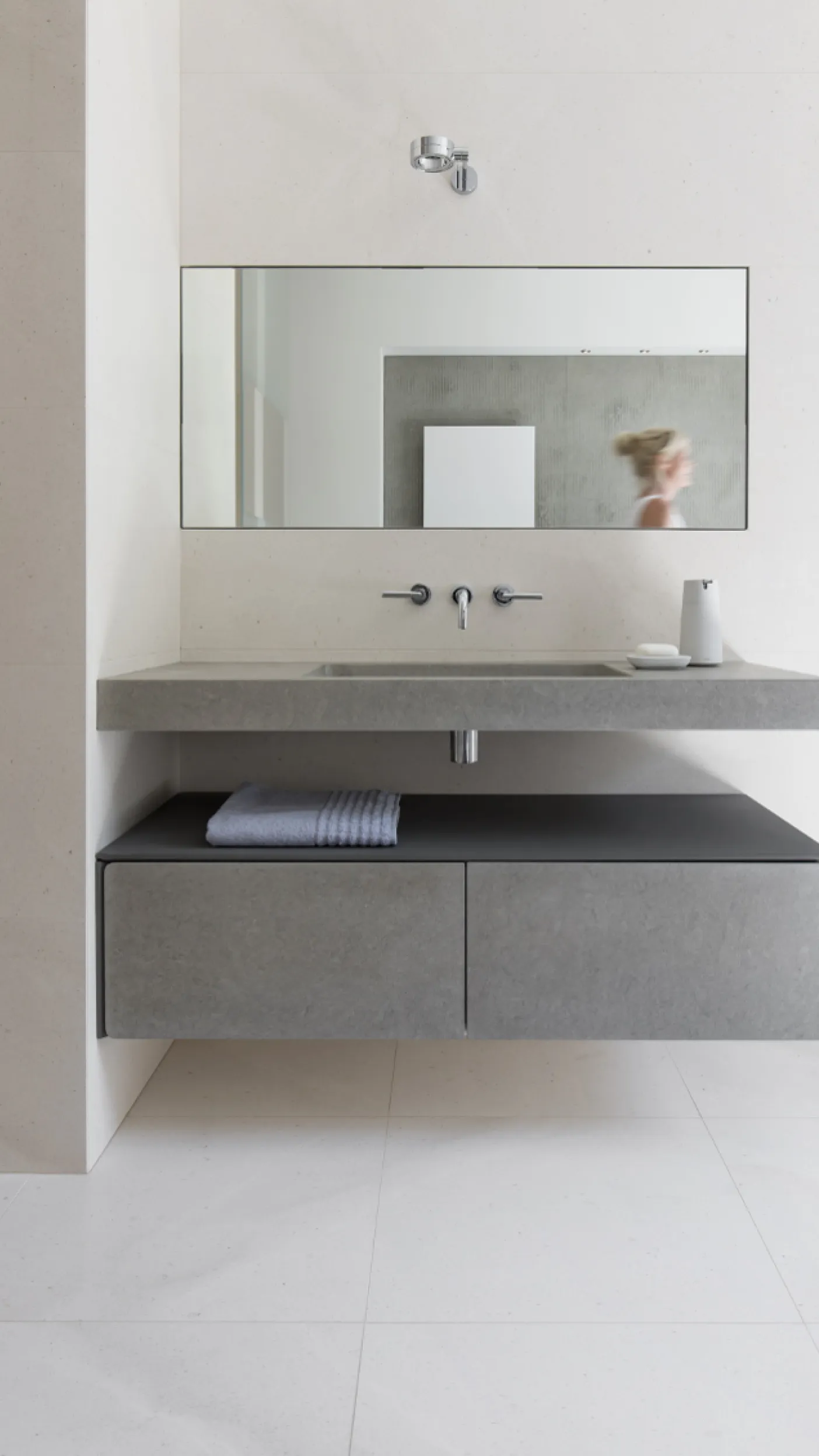 Helles Bad im Frankfurter Altbau mit minimalistischem Waschtisch und wandmontiertem Spiegel. Die Dusche ist durch eine Glaswand abgetrennt.