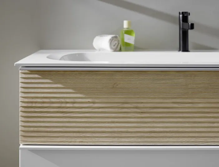 Nahaufnahme eines stilvollen Waschtisches der Marke burgbad Fiumo, der eine helle Holzschublade und eine klare weiße Oberfläche zeigt.